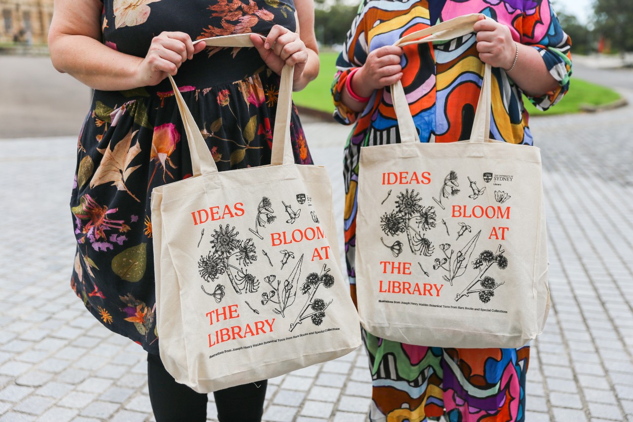 Two people holding Library canvas tote bags