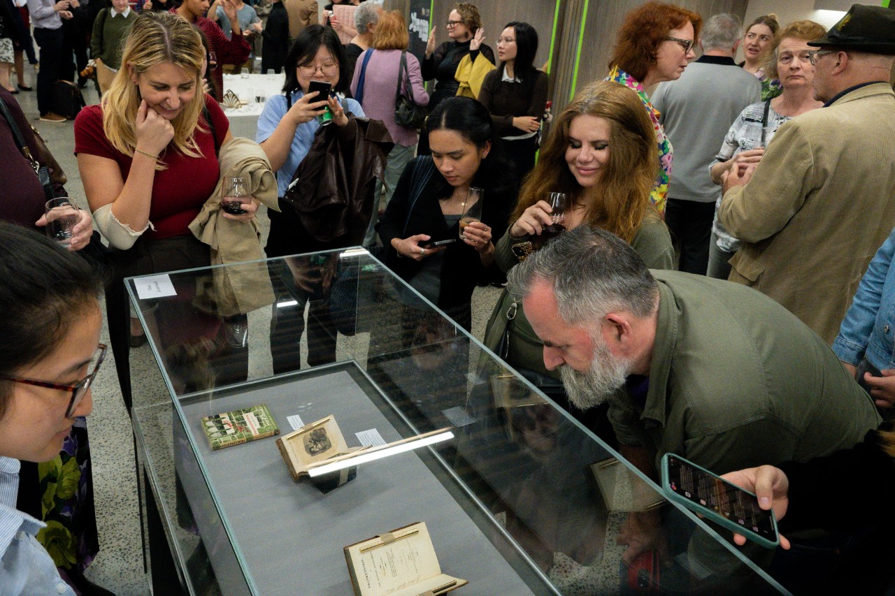 People viewing a display case with editions of Frankenstein on display