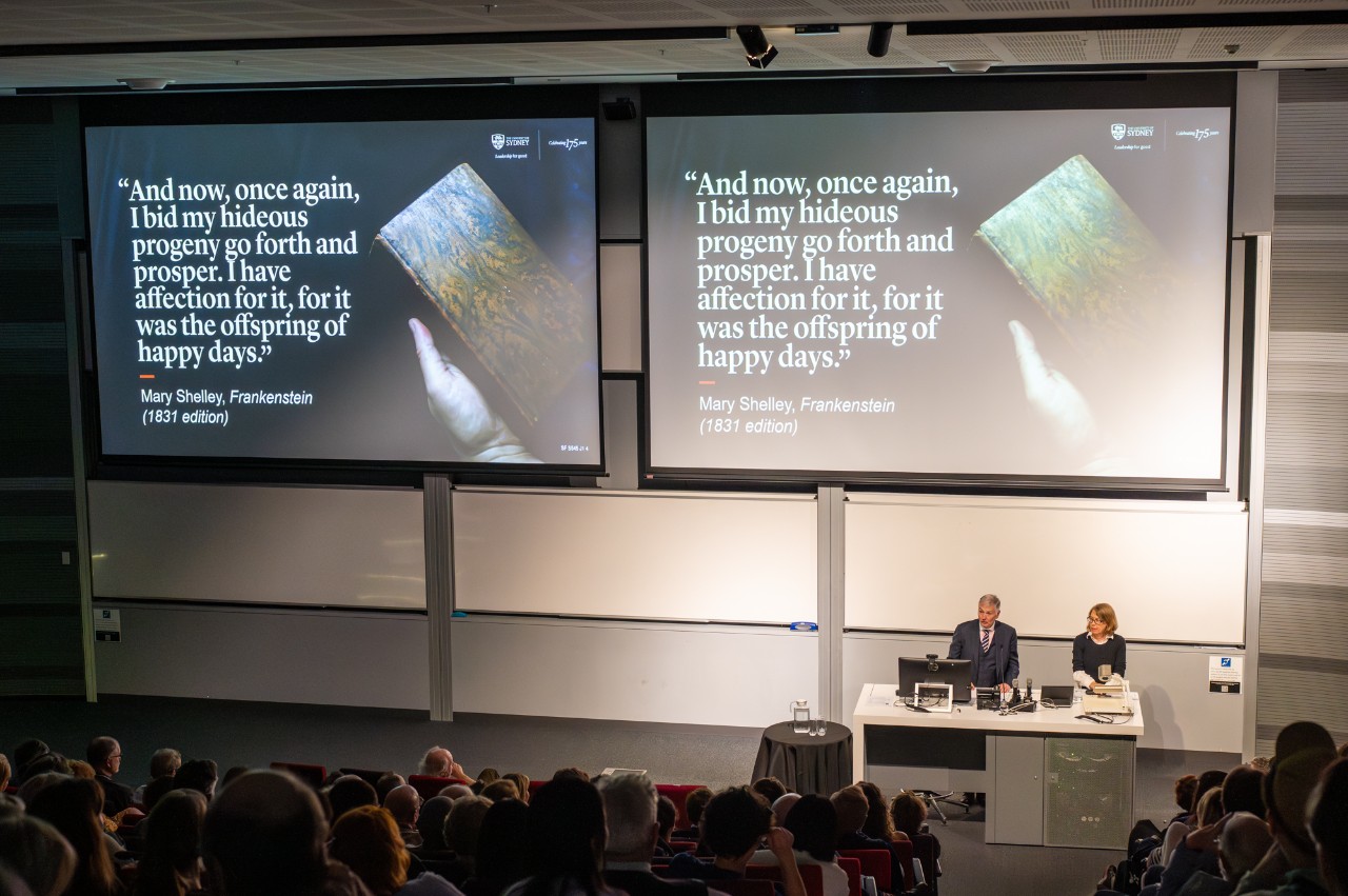 Philip Kent and Vanessa Smith speaking in front of a filled lecture theatre