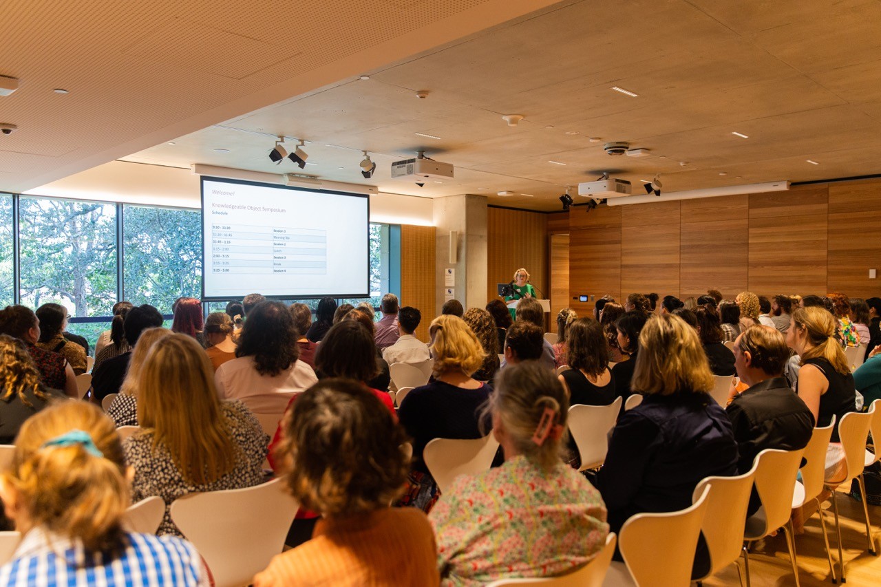 Wide shot of a speaker at a lectern in front of a large audience