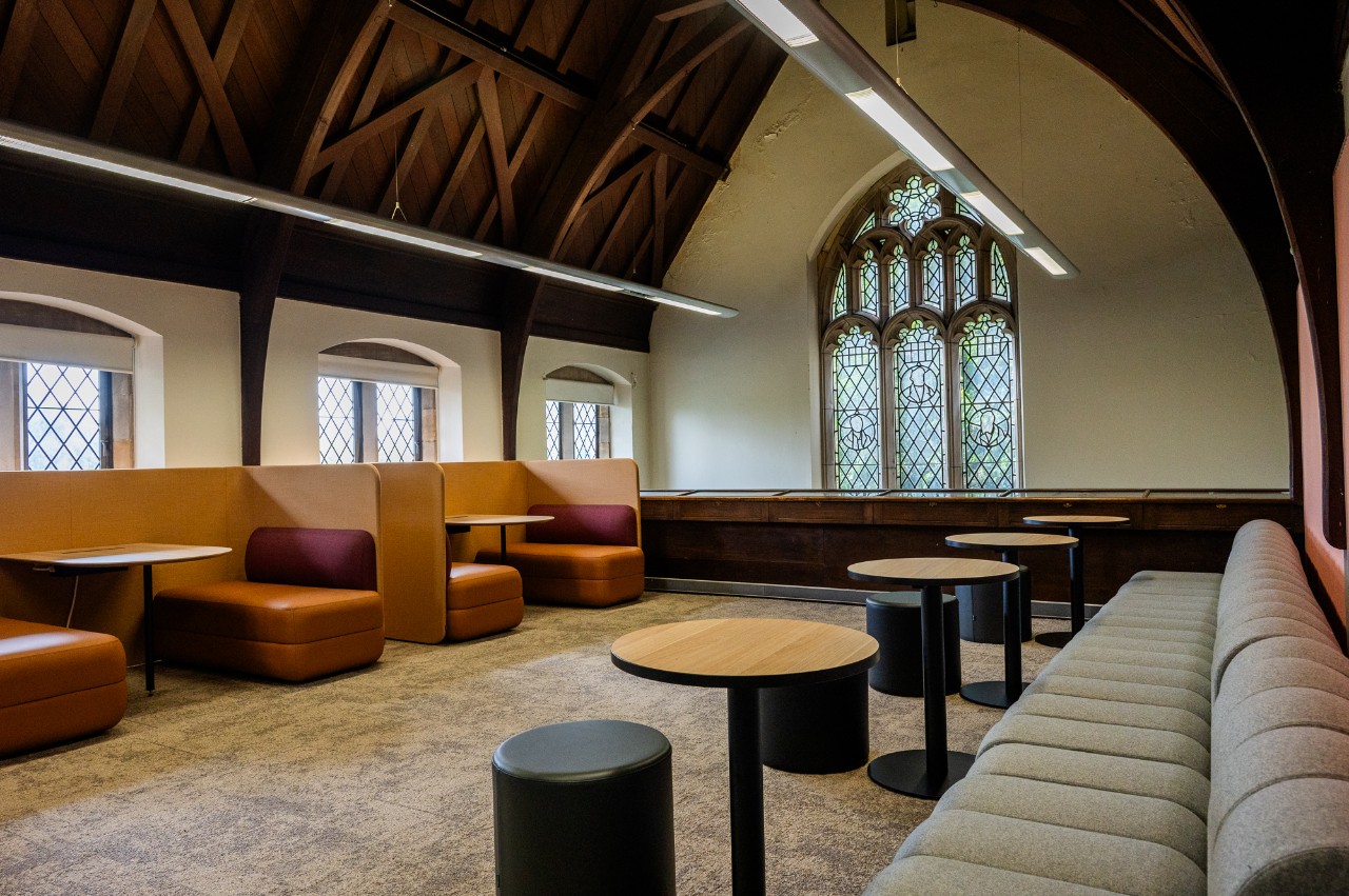 Interior view of a room with high arched ceiling, couches and small tables. 