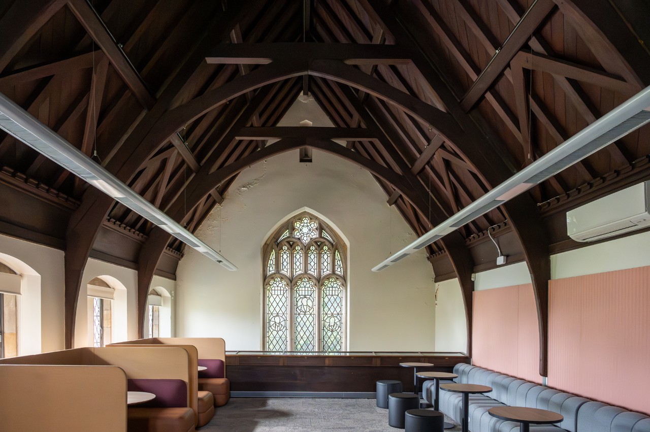 Interior view of a room with high arched ceiling, couches and small tables. 