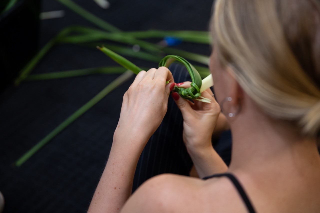 Person weaving with strands of grass