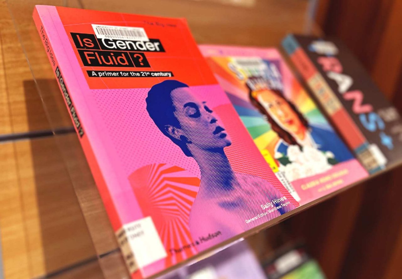 An angle shot of a pink and red pink cover, with a blurry focus of another two books