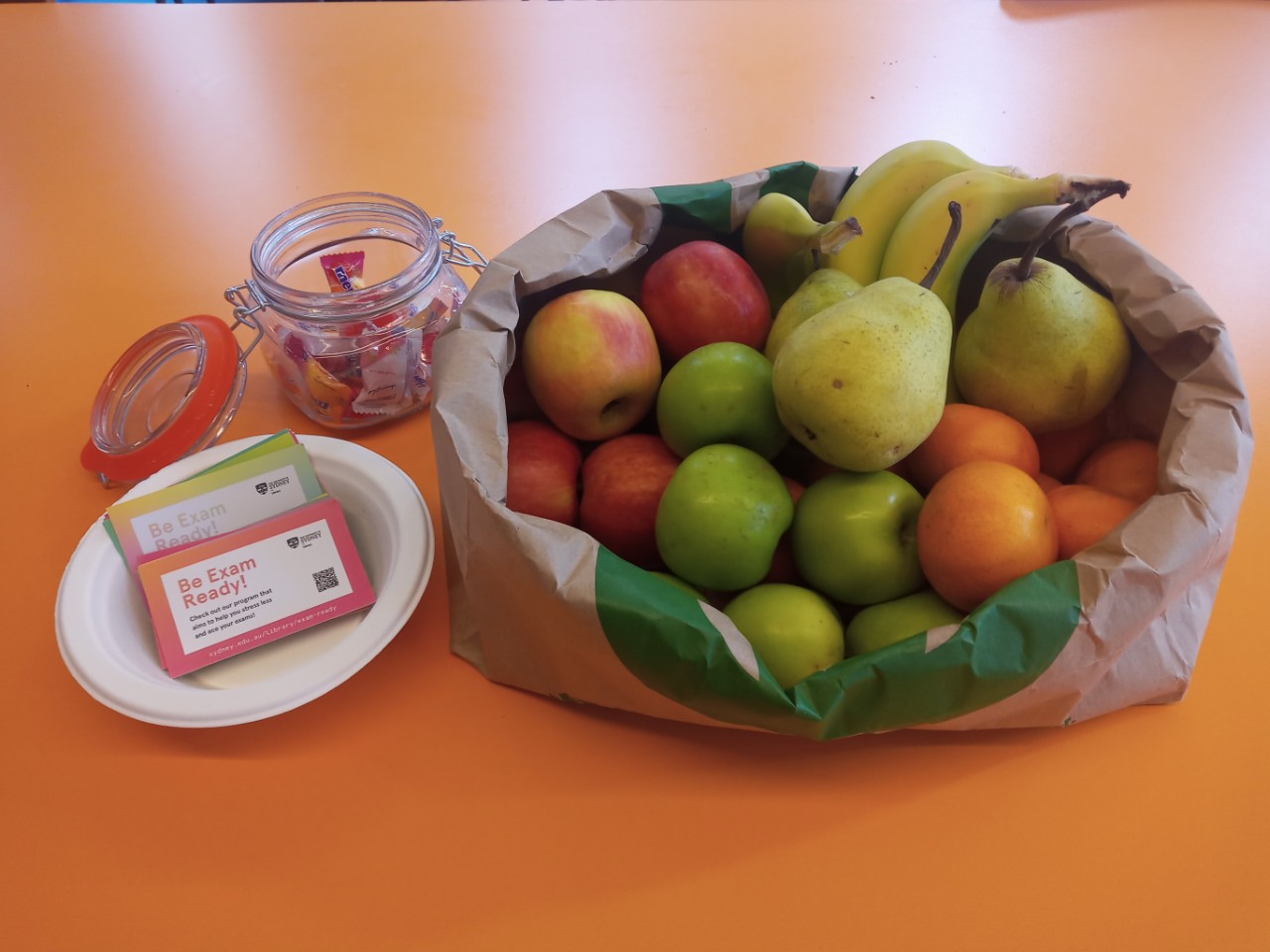 Library staff member handing out lollies to student in library