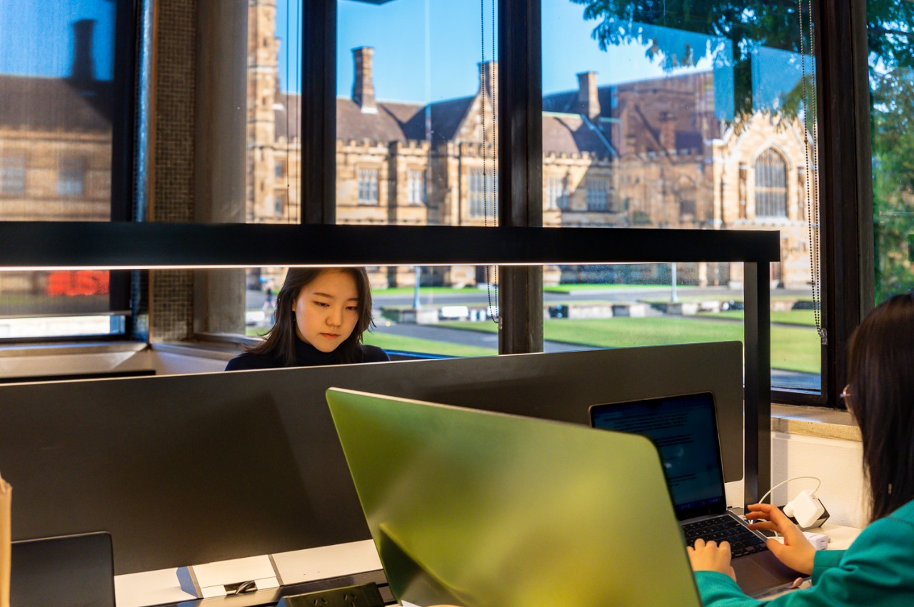 A student using a computer near a window in Fisher Library.