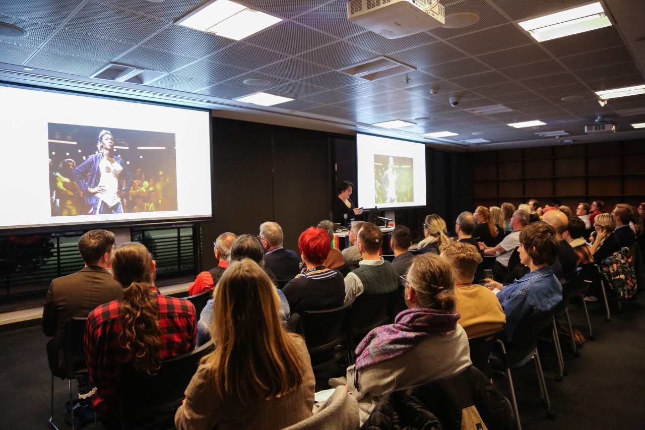 Sasha Bailey speaking in front of a large seated audience
