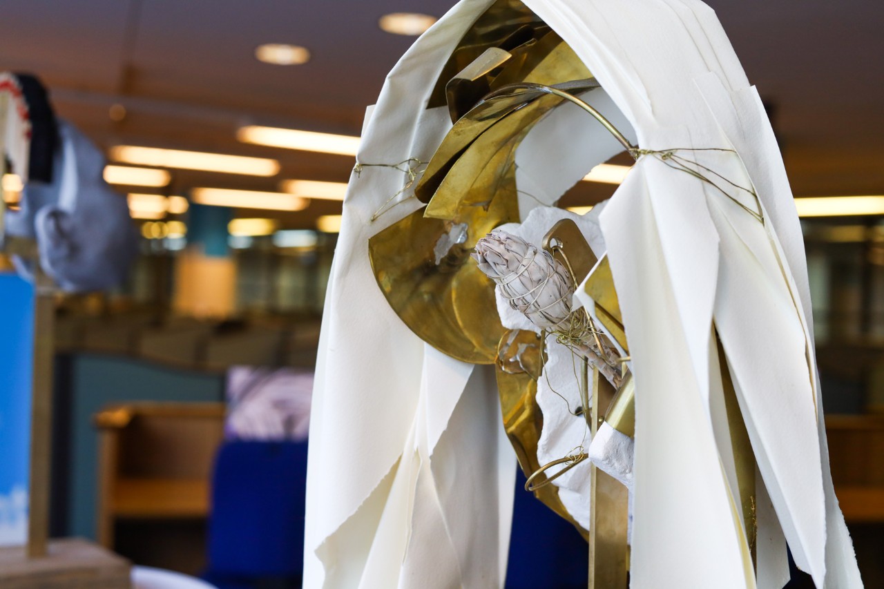 The back on the sculpture of Hildegard, showing bronze elements and a bundle of dried plants