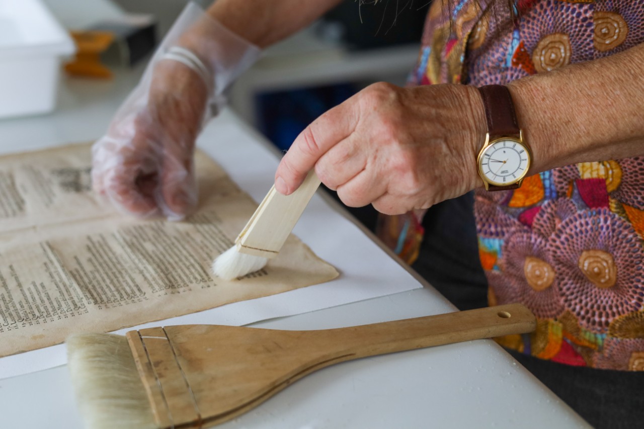 Conservator brushing a page from the rare book by Copernicus. 
