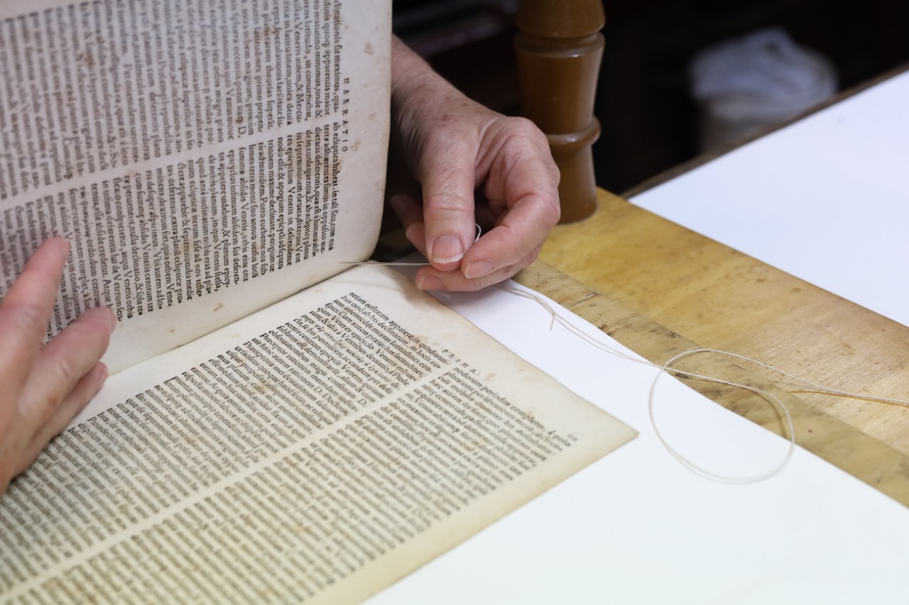 The conservator working on sewing the book together