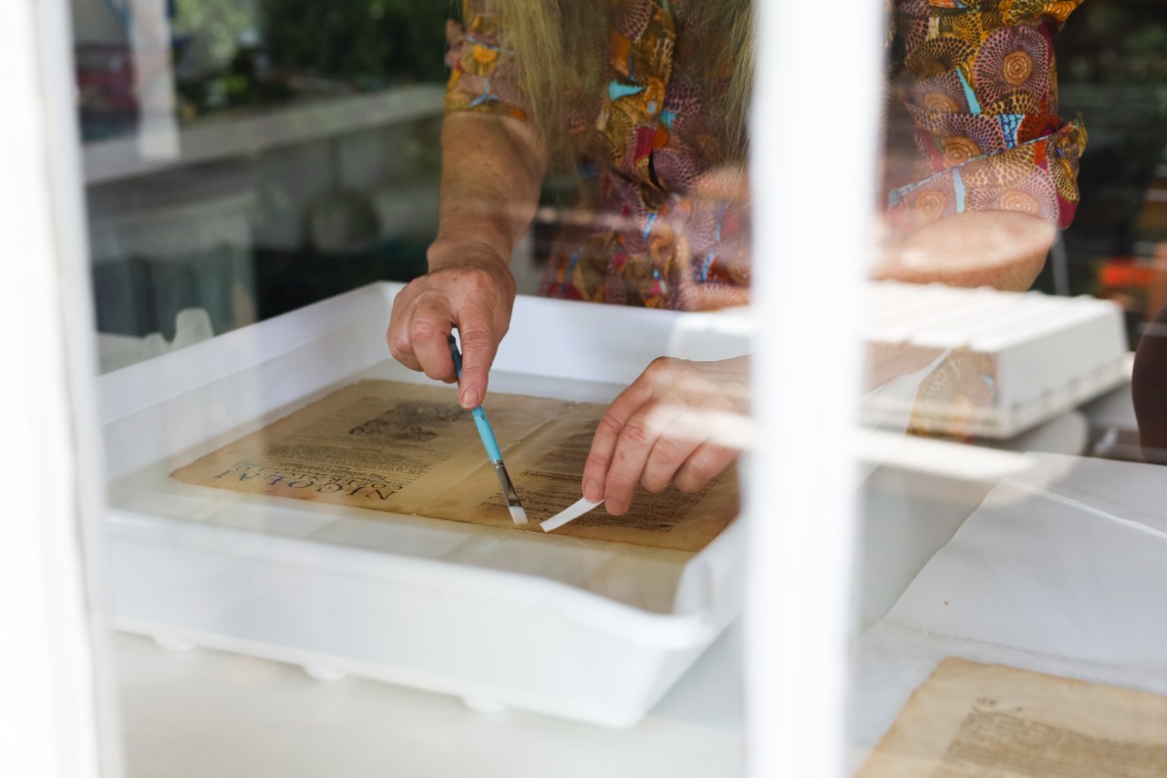 The conservator working on a page from Copernicus' book in a water bath