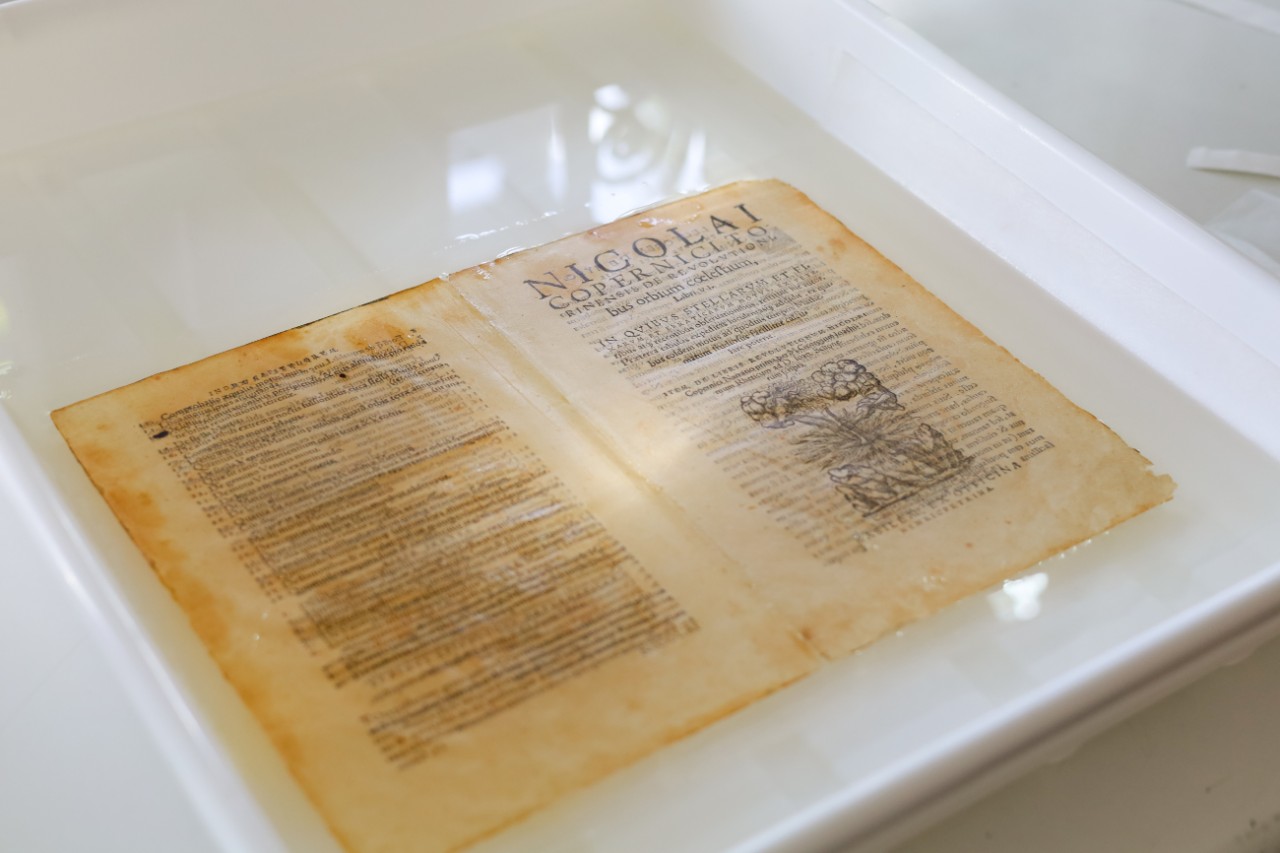 Close up of a book spread being washed in a water bath